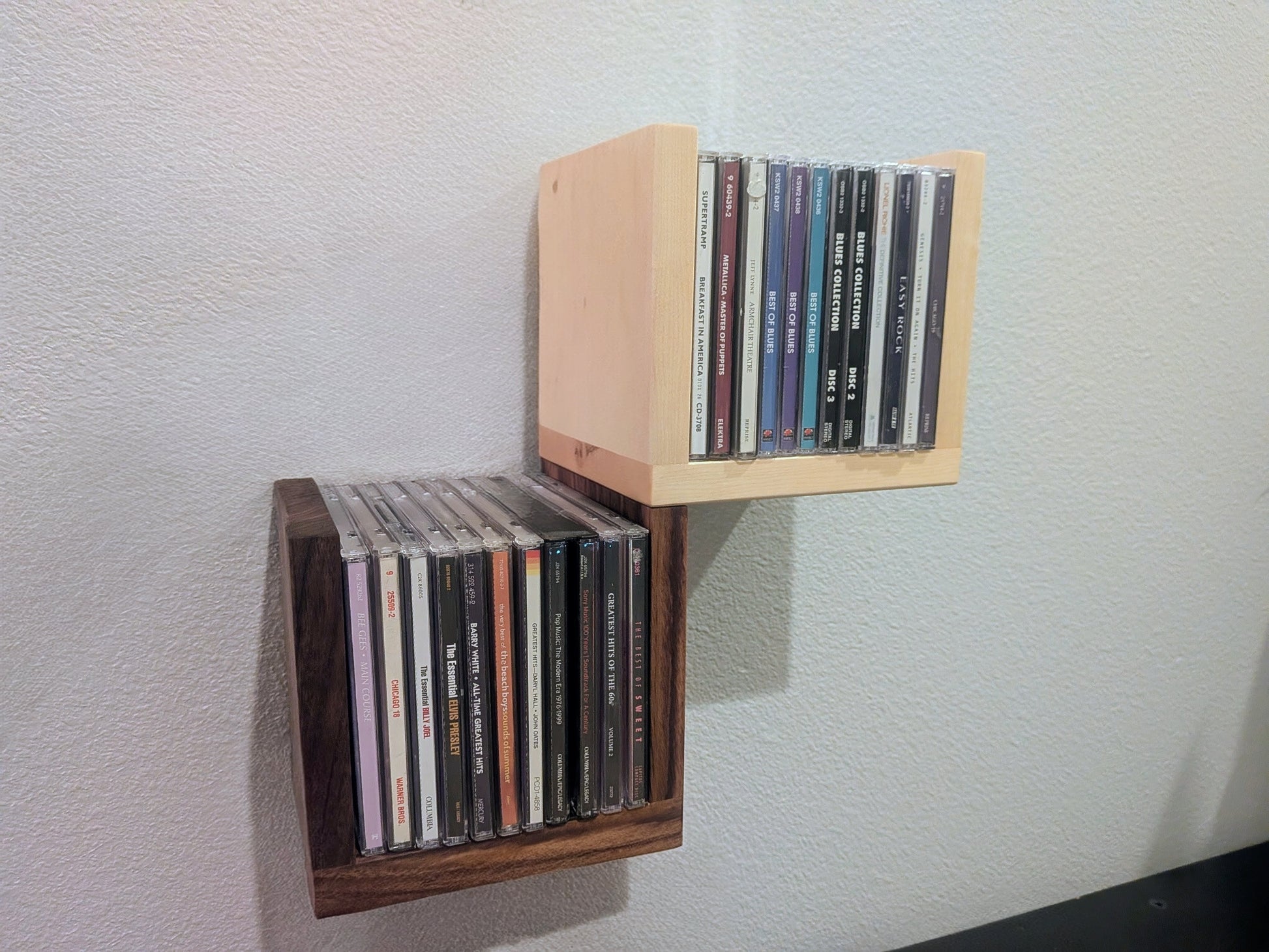 Wall-mounted CD holder with CDs on a light gray wall